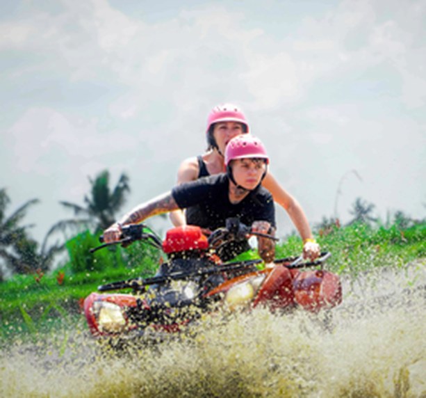 ATV quad bike splashing through a muddy track in Bali