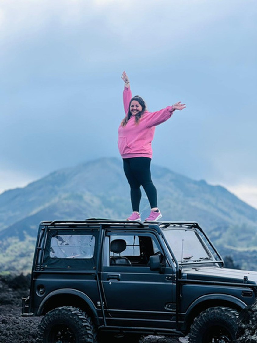Traveller standing on a jeep with Mount Batur behind